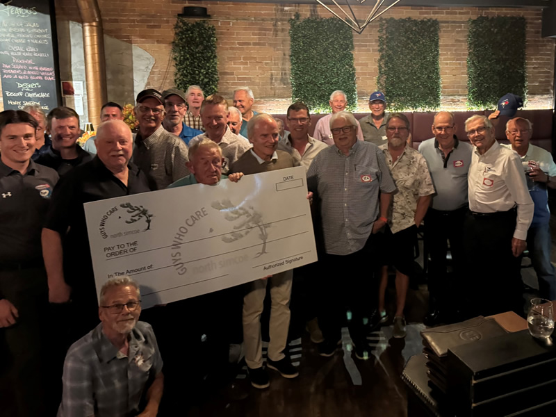 Guys Who Care group holding a cheque at the Fall meeting